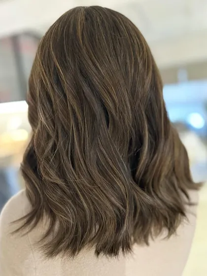 A warm-to-cool hair color transformation on mid-length hair. The cool-toned highlights give her a completely new and updated look.