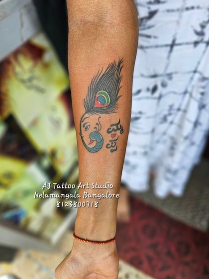 A creative design combining a peacock feather, a flute, and the names of 'Amma Appa' in Kannada.