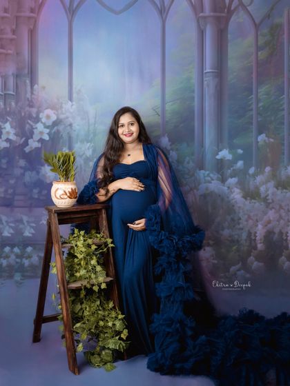A fairytale setting for a beautiful mom-to-be in a royal blue gown. The painted backdrop and rustic props create a truly enchanting scene.