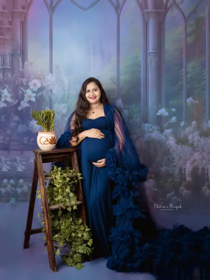 A fairytale setting for a beautiful mom-to-be in a royal blue gown. The painted backdrop and rustic props create a truly enchanting scene.
