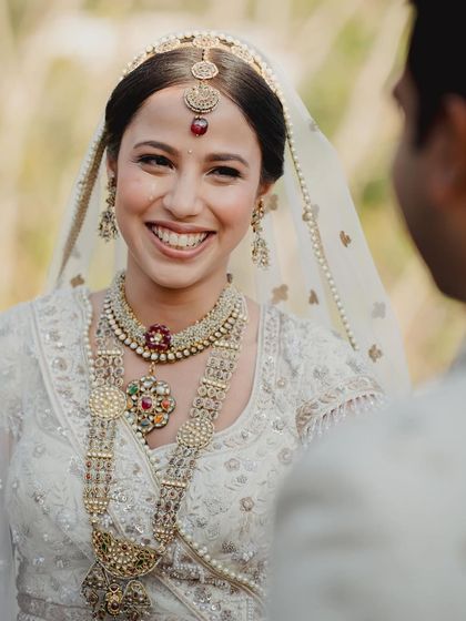 A candid, happy moment of a bride in a classic white Chikankari lehenga. The makeup is minimal and radiant, letting her joyful expression be the focus.