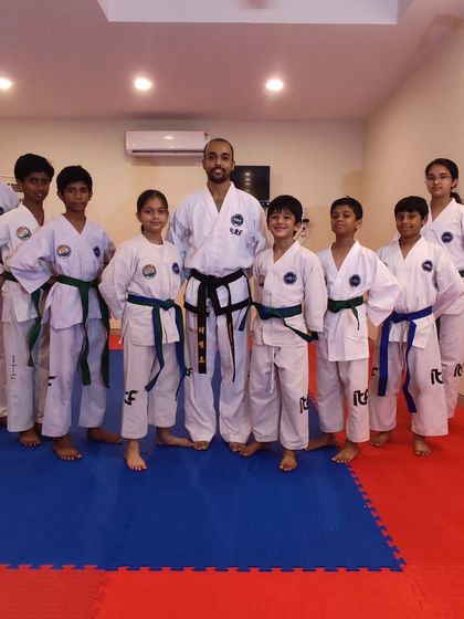 A group of our students who have just been promoted, standing together with their coach. Each new belt represents a milestone achieved.