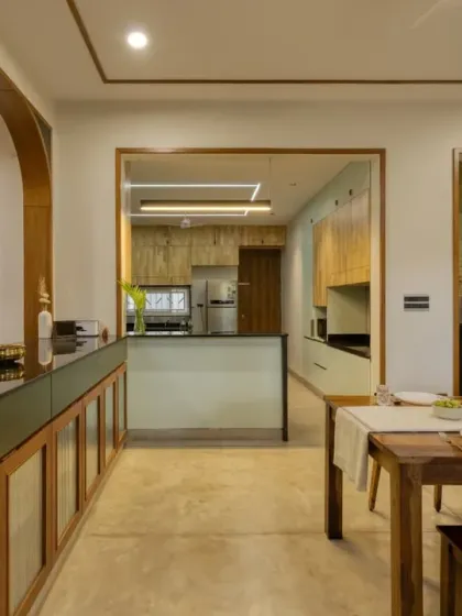 This perspective shows the open connection between the dining area and the mint-green kitchen in Villa 17, unified by warm wood and soft arches.