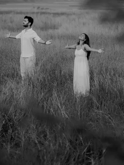A powerful black and white image of the couple standing in a tall grassy field with their arms outstretched, embracing the freedom of nature.
