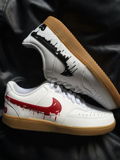 A pair of Nike Court Visions with a gum sole, featuring a red dripping heart on one shoe and a black one on the other.
