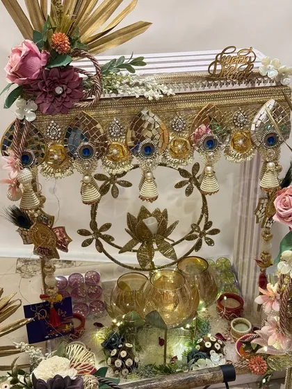 An opulent Diwali hamper with a beautiful lotus-themed brass hanging as the centerpiece. The arrangement is lit with fairy lights, creating a magical and festive feel.