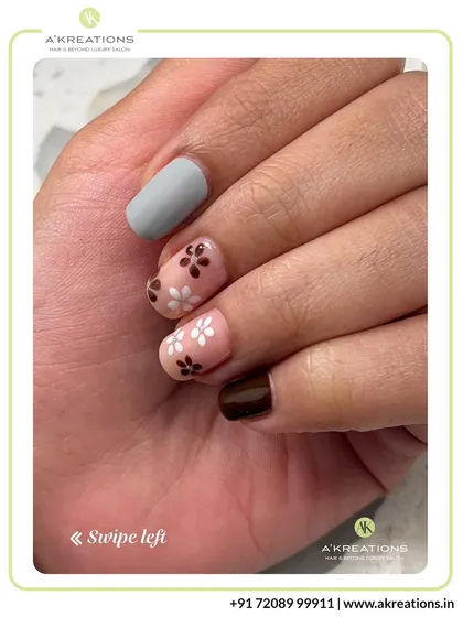 A close-up of the delicate brown and white floral nail art, highlighting the fine details and the contrast with the matte grey accent nail.