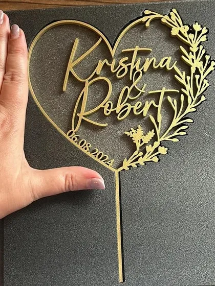 A heart-shaped topper for "Kristina & Robert" with floral details, showing the size and intricate design possibilities.