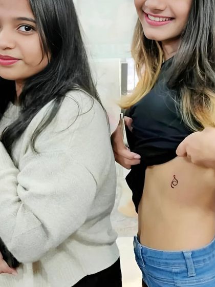 Two clients showing off their new tattoos, one on the wrist and one on the rib cage.