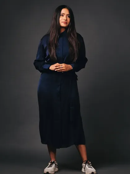 A full-length shot that combines a professional dress with casual sneakers. This is perfect for showing personality in a creative industry.
