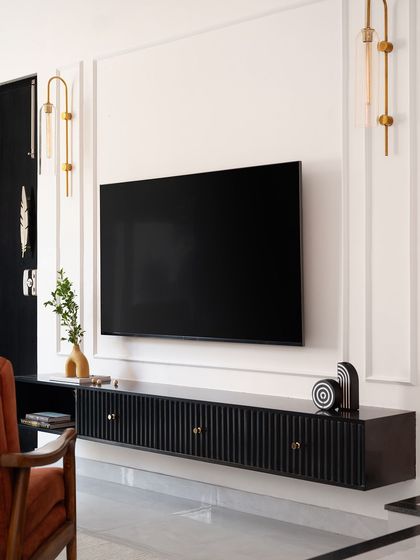 A sleek, floating TV unit in black with a fluted finish. Paired with gold handles and modern wall sconces, it makes a bold, sophisticated statement.