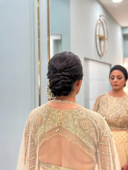 A clean twisted bun, viewed from the side, showing the bride's reflection in the mirror.