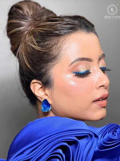 A pop of color can transform a whole look. For this modern party style, I used a sharp, electric blue winged liner to create a statement eye, balanced with glowing skin and a neat top knot for a chic and unforgettable finish.
