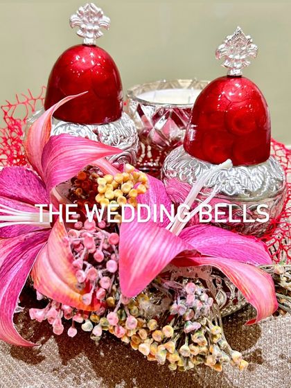 This luxurious Diwali hamper features two silver-plated jars with red lids and a silver candle, all arranged on a beautiful brass urli.