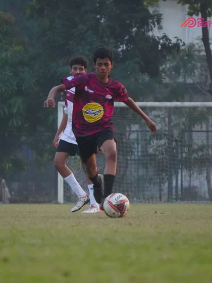 A player skillfully dribbles the ball while fending off a defender.