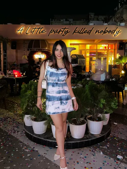 Posing in front of the "A Little Party Killed Nobody" sign at Veu. This captures the fun and energetic vibe of the place.