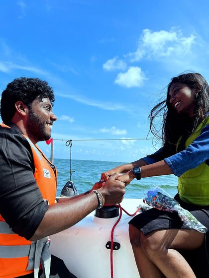 A tender moment between the newly engaged couple, holding hands against the backdrop of the sea and sky.