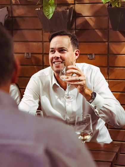 A guest smiling while enjoying a glass of white wine at our Indiranagar soirée.