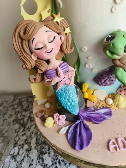 A close-up of the mermaid figurine from the underwater-themed cake, showing her serene expression as she holds a starfish.