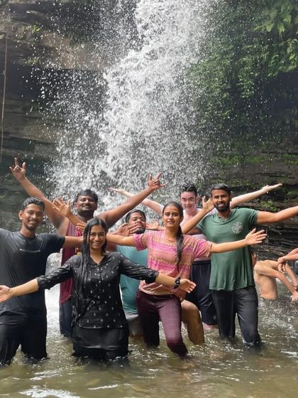 A group of friends with arms outstretched, enjoying the refreshing spray of Soormane waterfalls.