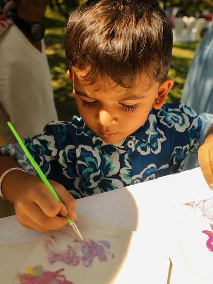 Even the youngest guests can get involved. Here, a little boy is completely focused on painting his own masterpiece at a wedding event.