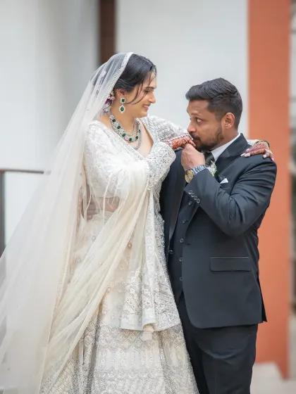 A chivalrous gesture as the groom kisses his bride's hand. It's a classic, romantic moment that makes for a beautiful photograph.
