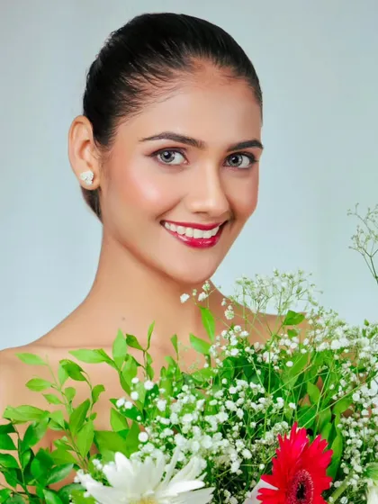 A sweet and simple beauty shot. The model's direct gaze and gentle smile, combined with the fresh flowers, create a lovely, approachable portrait.