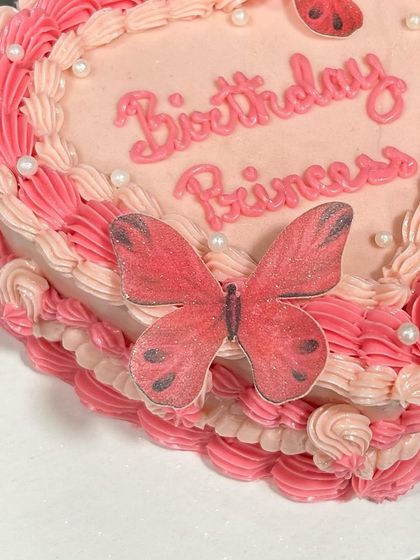 A close-up of the "Birthday Princess" text and edible butterfly on this vintage heart cake.