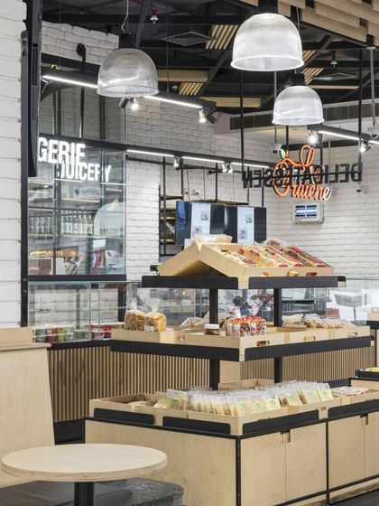 The bakery and juicery section at Le Marche features its own distinct identity within the larger store. The use of neon signage and dedicated display cases creates a lively 'shop-in-shop' feel, enhancing the customer experience.