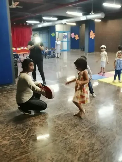 A young girl learns to strike a pad during a playschool workshop. These early lessons are crucial for building confidence and body awareness.
