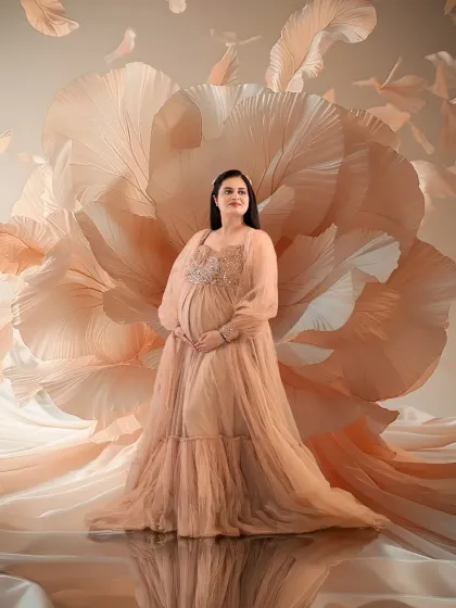 Soft, dreamy, and ethereal. The mom-to-be is surrounded by a cloud of flowing peach fabric and petals, wearing a matching sequined gown that exudes pure grace.