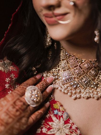 A detailed close-up of the bride's jewelry and henna. This shot highlights the intricate craftsmanship of her necklace and the beautiful Mehendi design.