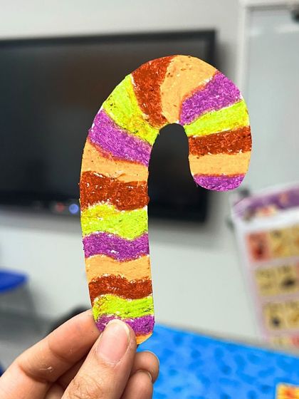 A colorful candy cane ornament made with oil pastels by a young student during our Christmas workshop.