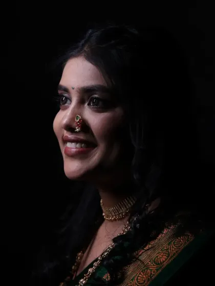 A profile shot of a smiling bride, captured with dramatic lighting. The minimal makeup enhances her natural features and joyful expression.