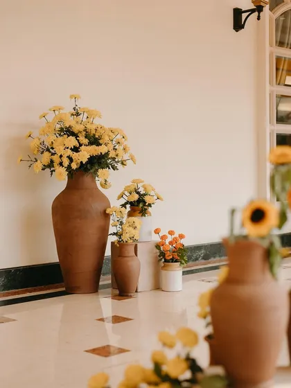 Large terracotta vases filled with yellow chrysanthemums, showcasing our use of simple, beautiful, and sustainable materials.
