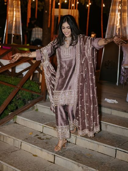 A guest shows off her henna-adorned hands while making a graceful entrance at the Mehendi night.