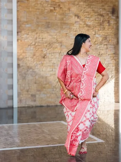 A dynamic shot of a couple walking through a modern space in their traditional outfits.