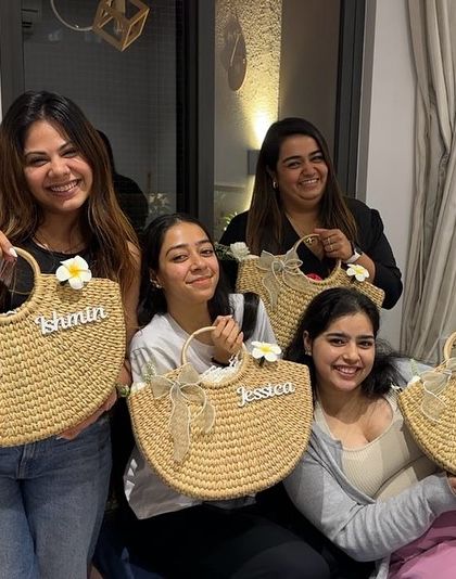 A group of happy bridesmaids showing off their personalized wicker tote bags. These are a great practical gift that they can use long after the wedding day.