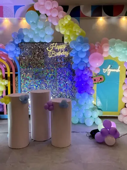 A pastel rainbow Cocomelon theme with a silver sequin backdrop. This large-scale decoration includes rainbow props, 'BABY' blocks, and multiple character cutouts.