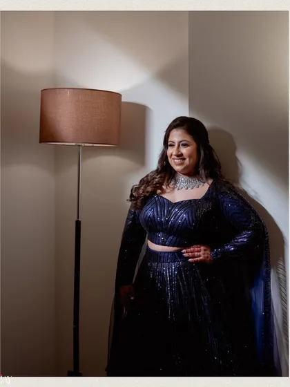 A simple and elegant solo portrait of the bride. The soft, directional lighting beautifully illuminates her features and the details of her sequined outfit.