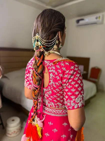 Perfect for a fun Mehendi or Haldi event, this creative braid is woven with colorful threads and bright tassels. It's a playful yet traditional style, finished with a pearl hair accessory for an extra touch of elegance.