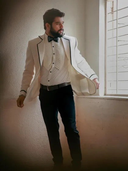 A candid moment from the shoot with Kshitish Date. The white tuxedo jacket with its pleated shirt detail offers a modern take on classic formalwear.