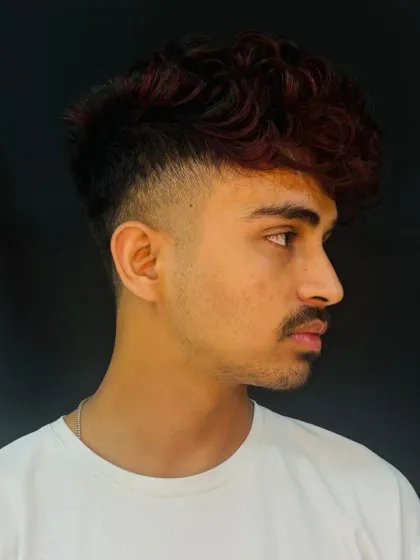 We teach our students to create modern, edgy looks that are in high demand. This men's haircut features a sharp fade combined with bold red highlights, demonstrating skills in both precision cutting and creative coloring.