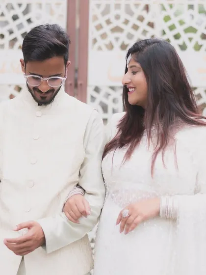 A candid moment of a couple walking together, dressed in elegant white. Their shared glance and easy smiles reflect the comfortable love between them during their pre-wedding shoot.