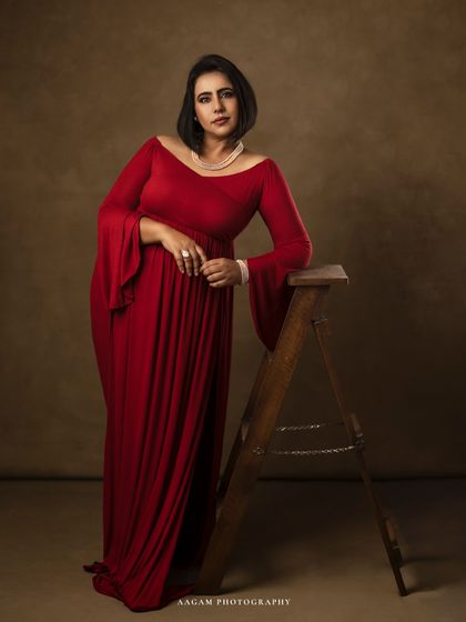 A full-length view of the same elegant red gown, showing its beautiful drape and the mother's graceful stance.