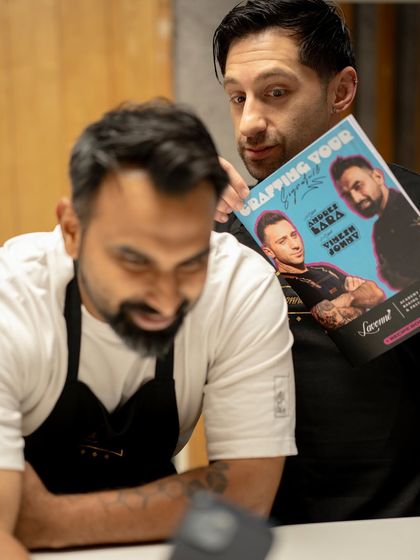 A fun moment behind the scenes with Chefs Andres Lara and Vinesh Johny, holding the poster for their "Crafting Your Signature" masterclass.