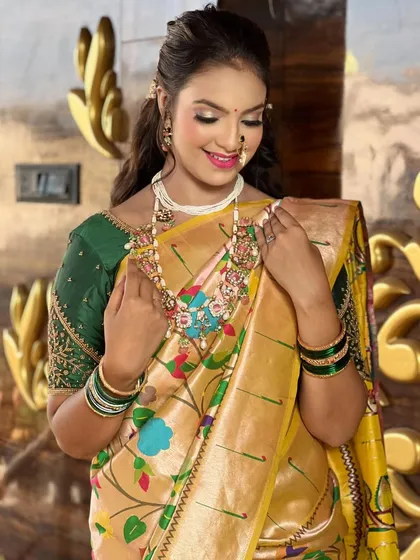 A graceful pose showing the intricate floral patterns of the `Paithani` saree and the heavy bridal jewelry.