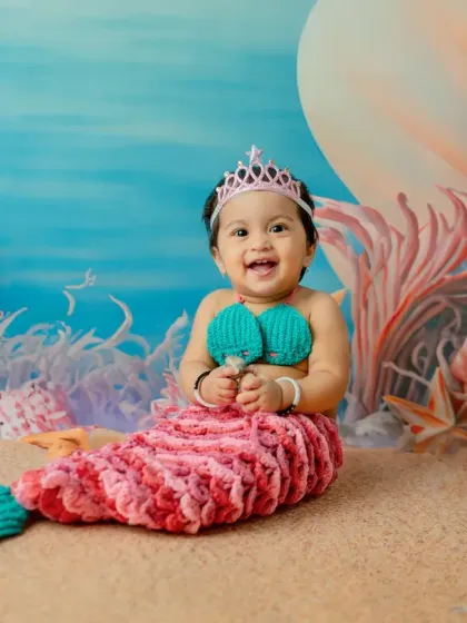 A full-body shot showing the complete mermaid costume, from the knitted shell top to the detailed fin. The baby's happy expression makes this photo truly special.