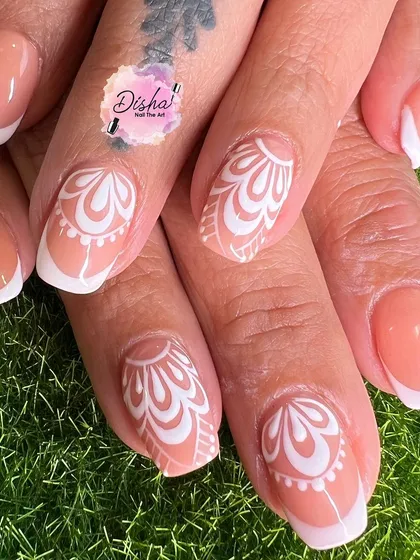 Classic and chic. This design features a French manicure base with intricate white patterns on the accent nails, creating a timeless and elegant look.