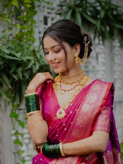 A beautiful bride in a magenta saree. Her soft, elegant updo is accented with a chain accessory, adding a touch of modern style to her traditional look.